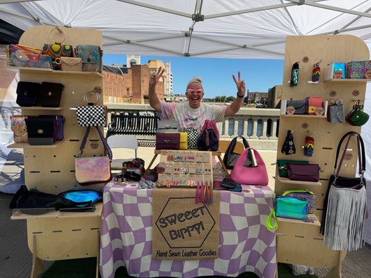 Market booth showing colorful hand sewn leather goods by Sweeet Bippy