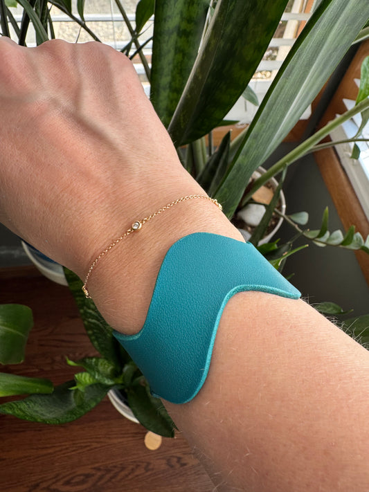 Handmade wavy leather bracelet in teal worn on wrist, minimalist colorful leather jewelry by Sweeet Bippy